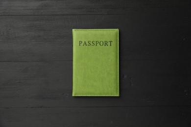 Photo of Passport in green cover on black wooden table, top view