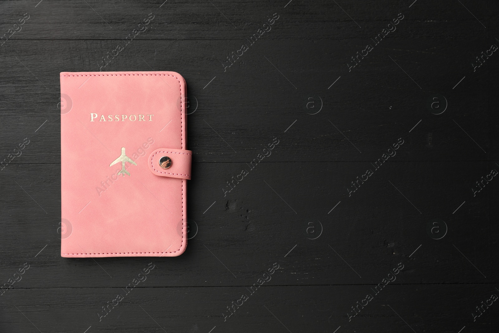 Photo of Passport in pink cover on black wooden table, top view. Space for text