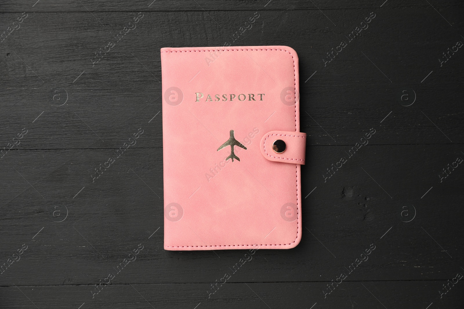 Photo of Passport in pink cover on black wooden table, top view