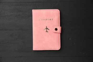 Photo of Passport in pink cover on black wooden table, top view