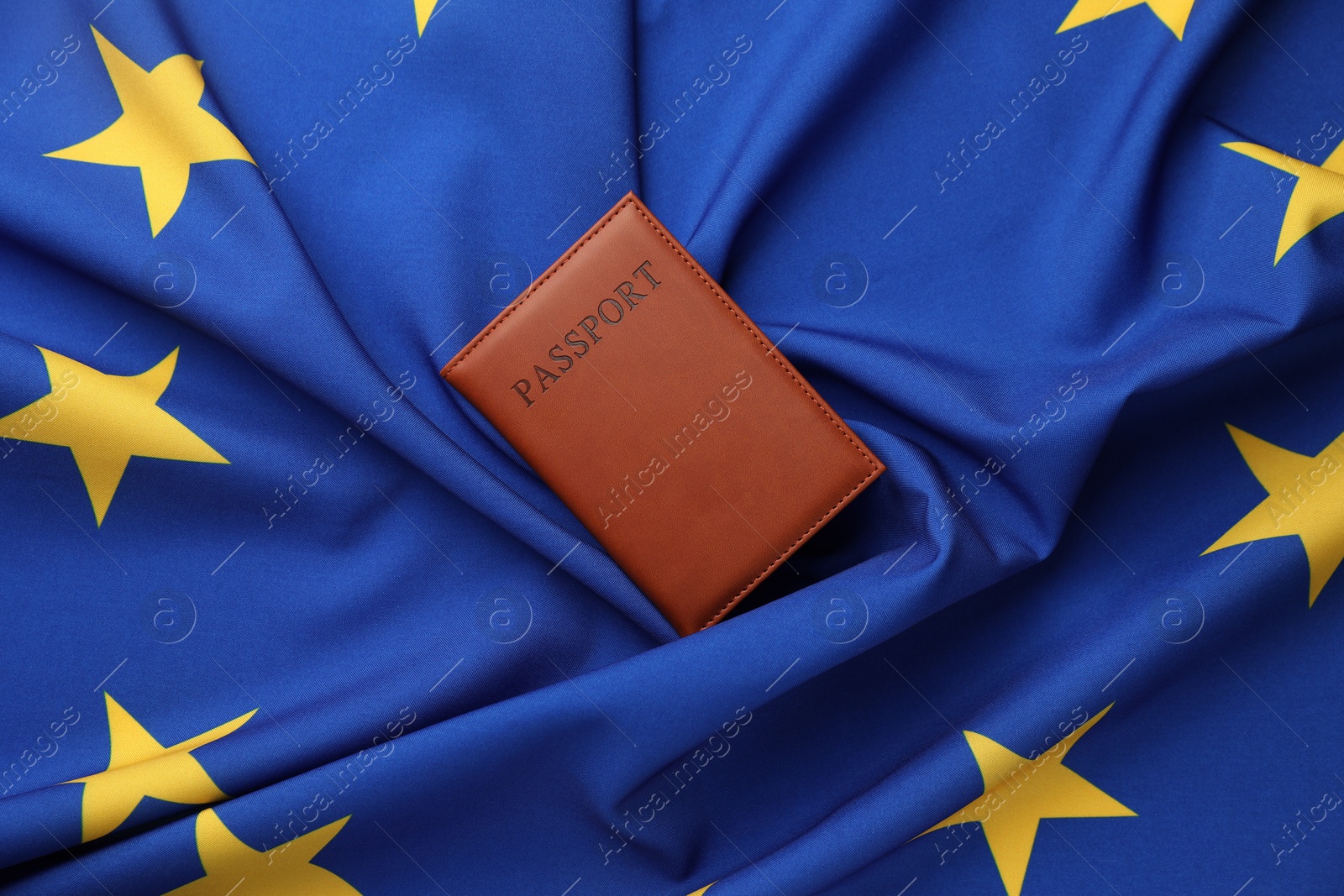 Photo of Passport in brown cover on flag of European Union, top view