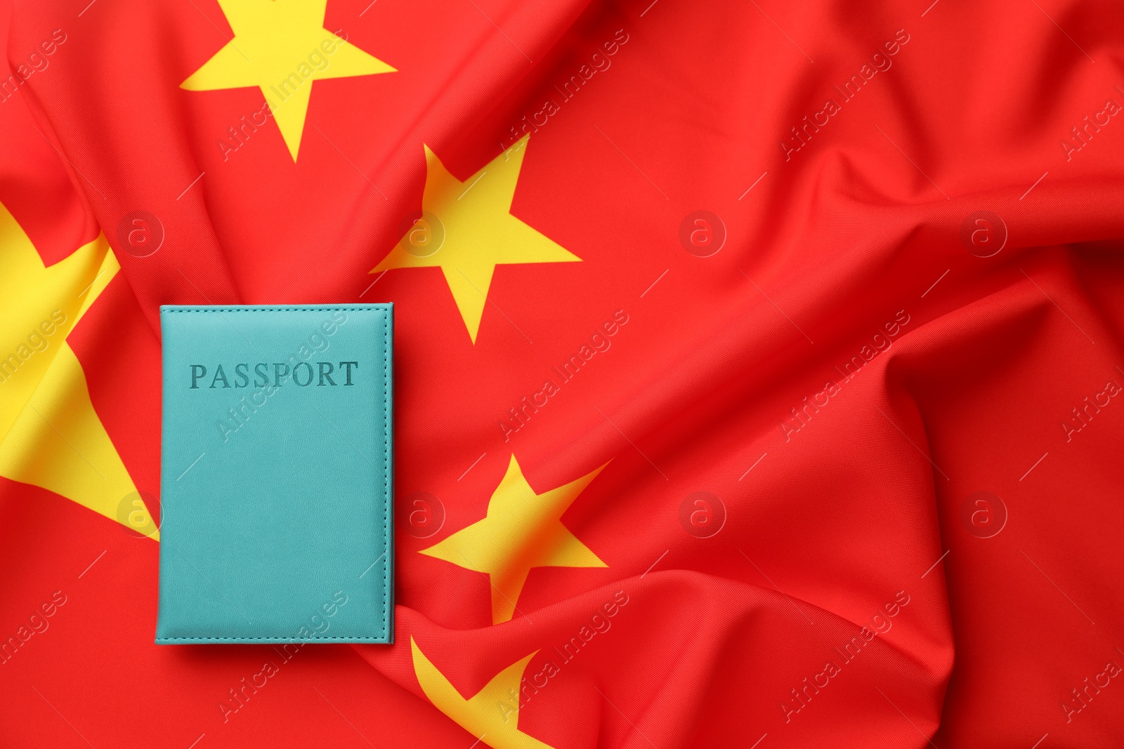 Photo of Passport in light blue cover on flag of China, top view. Space for text