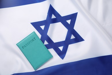 Photo of Passport in light blue cover on flag of Israel, top view. Space for text