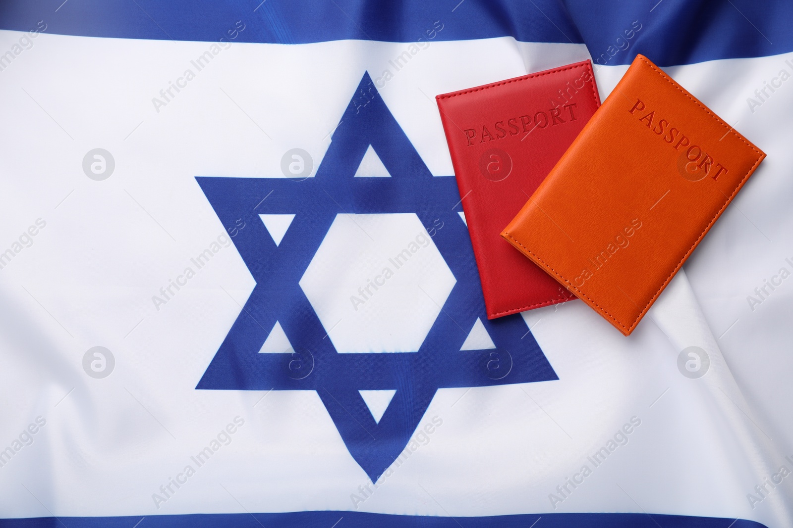 Photo of Passports in color covers on flag of Israel, top view. Space for text