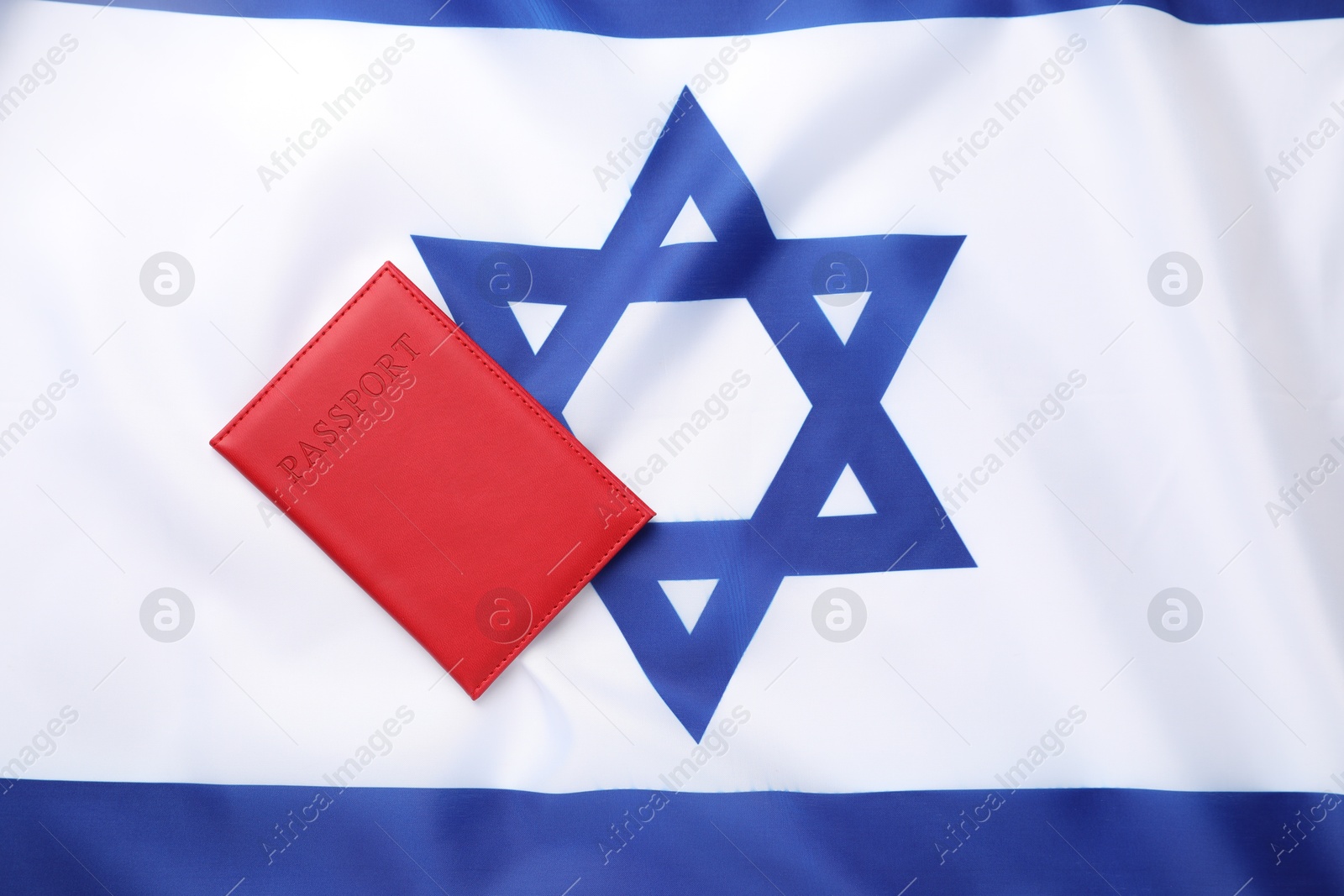 Photo of Passport in red cover on flag of Israel, top view. Space for text