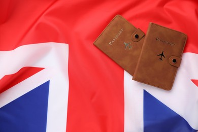 Photo of Passports in brown covers on flag of United Kingdom, top view. Space for text