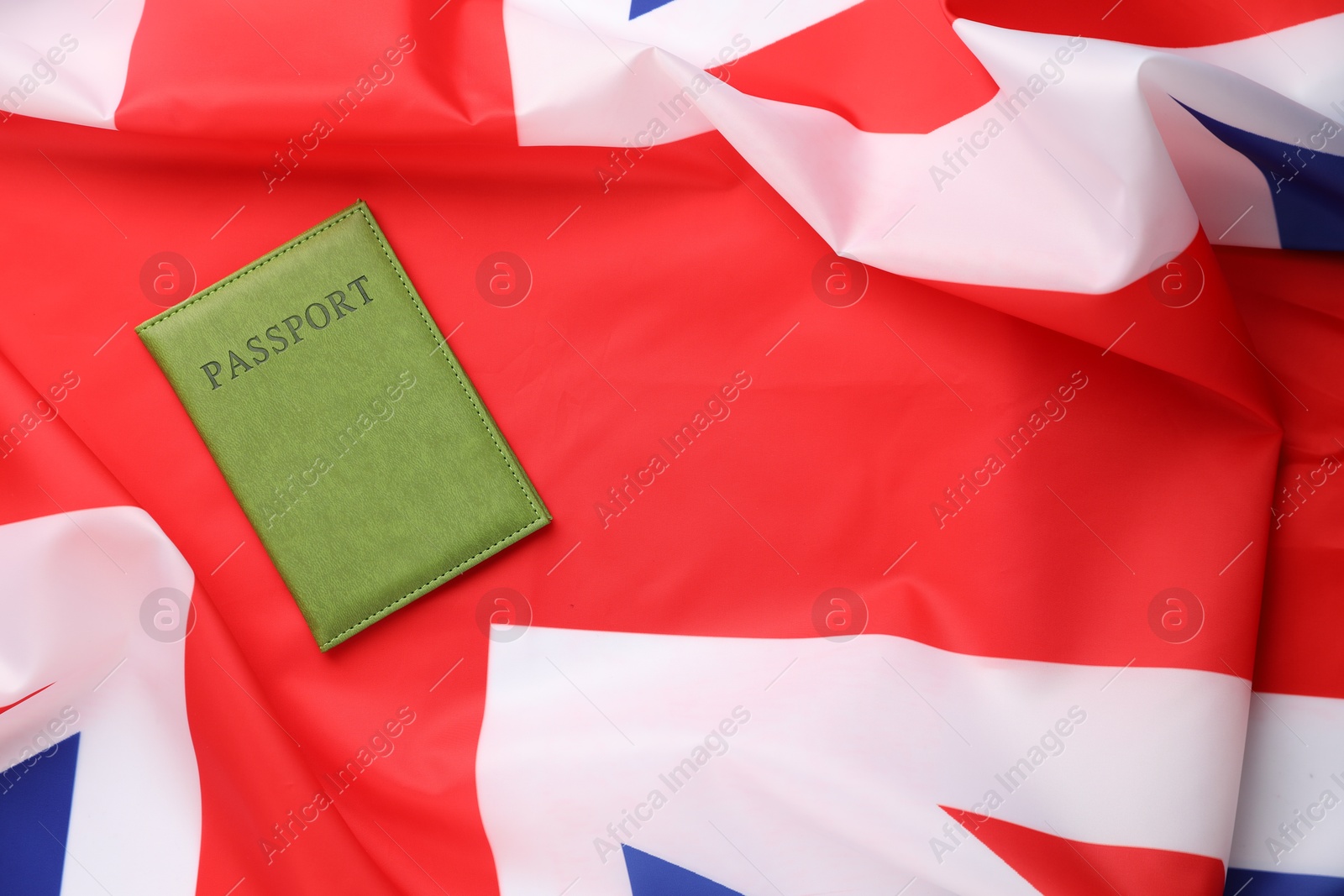 Photo of Passport in green cover on flag of United Kingdom, top view. Space for text