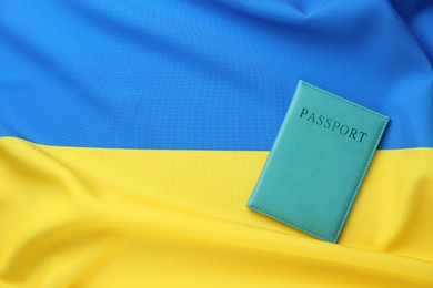 Photo of Passport in light blue cover on flag of Ukraine, top view. Space for text