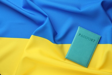 Photo of Passport in light blue cover on flag of Ukraine, top view. Space for text