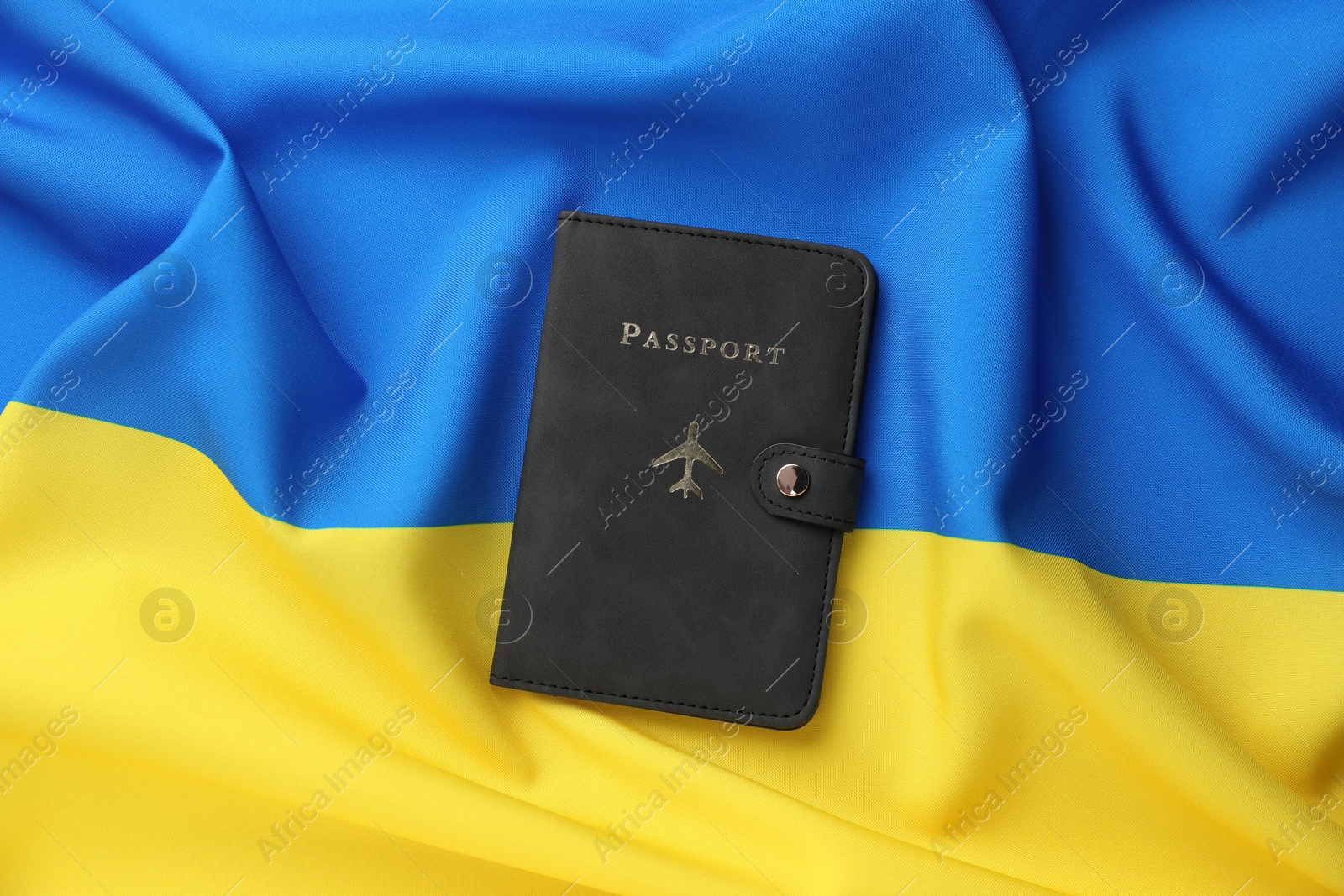 Photo of Passport in black cover on flag of Ukraine, top view