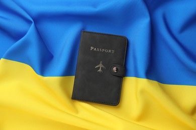 Photo of Passport in black cover on flag of Ukraine, top view