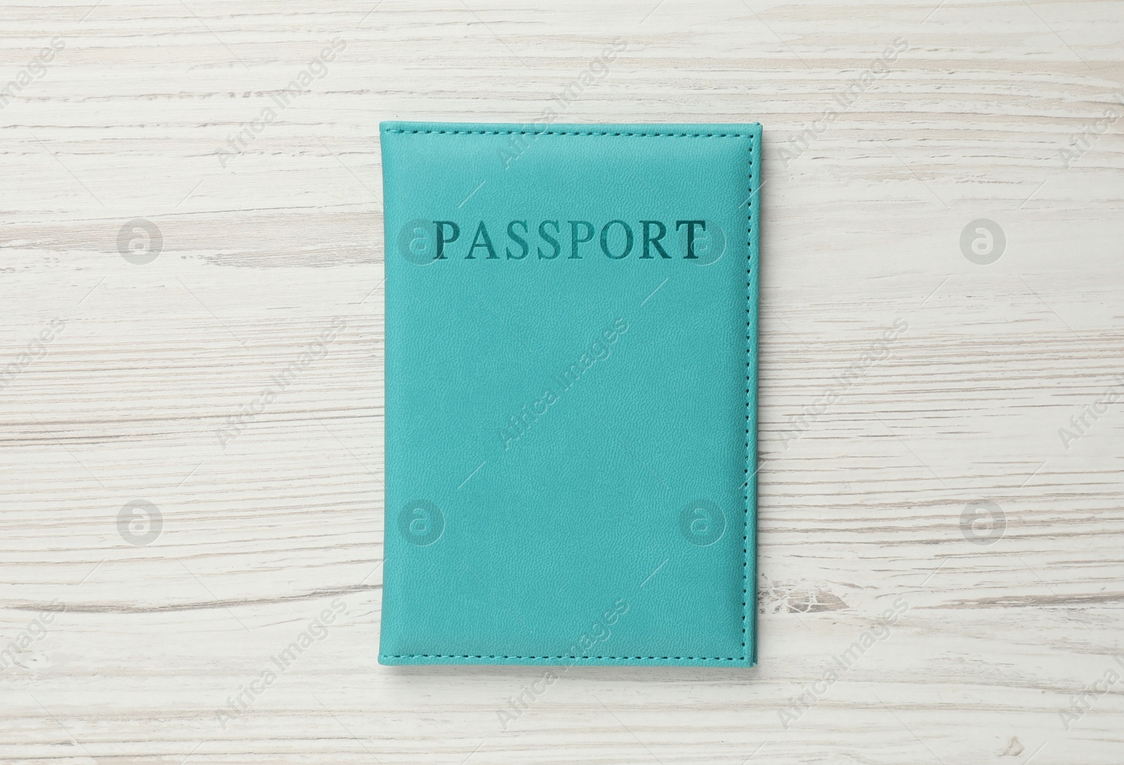 Photo of Passport in light blue cover on wooden table, top view