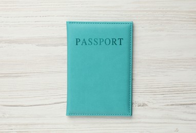 Photo of Passport in light blue cover on wooden table, top view