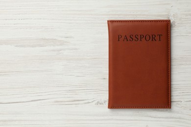 Photo of Passport in brown cover on light wooden table, top view. Space for text