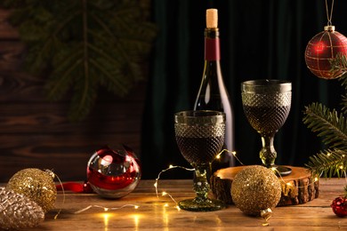 Photo of Red wine and beautiful Christmas decor on wooden table. Space for text