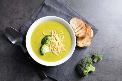 Photo of Delicious broccoli cream soup served on gray textured table, flat lay