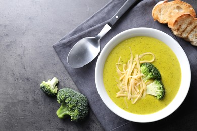 Photo of Delicious broccoli cream soup served on gray textured table, flat lay. Space for text