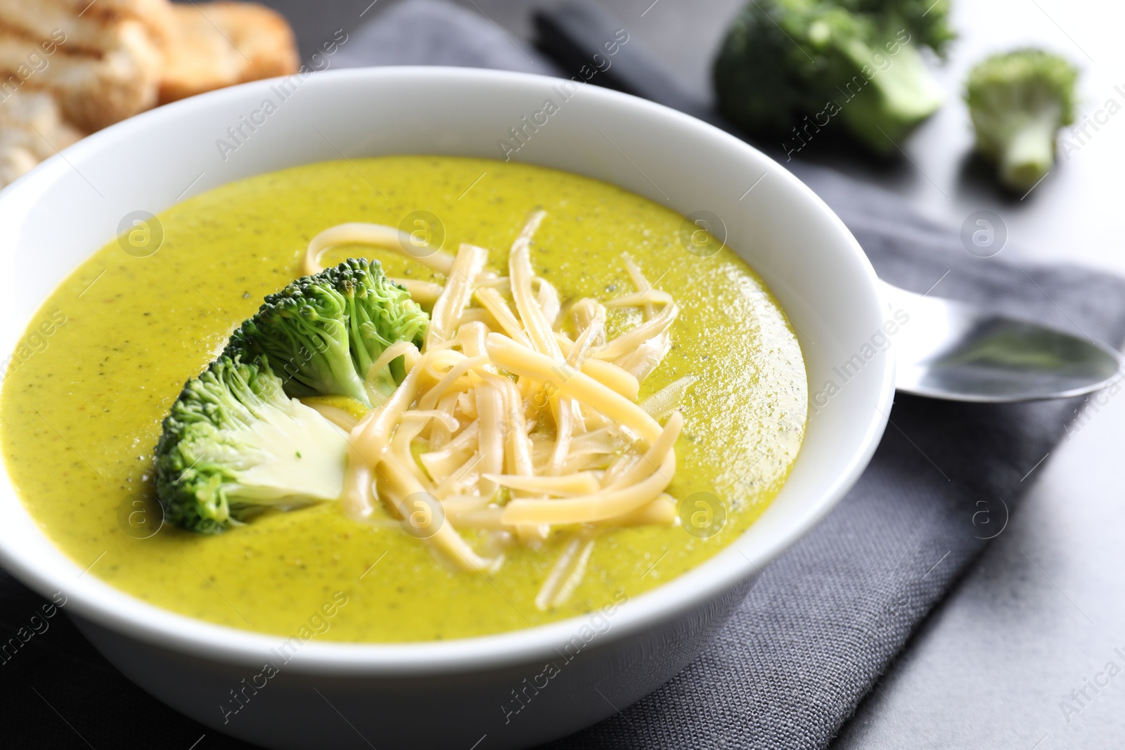 Photo of Delicious broccoli cream soup served on gray table, closeup