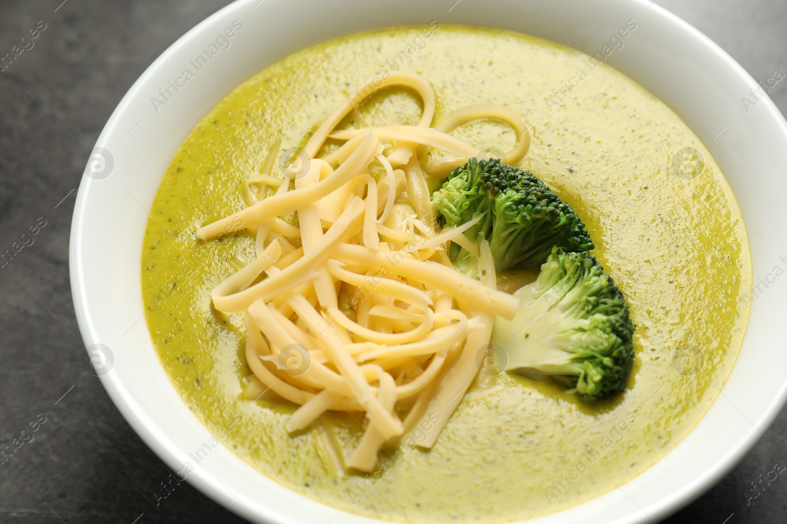 Photo of Delicious broccoli cream soup in bowl on gray table, closeup