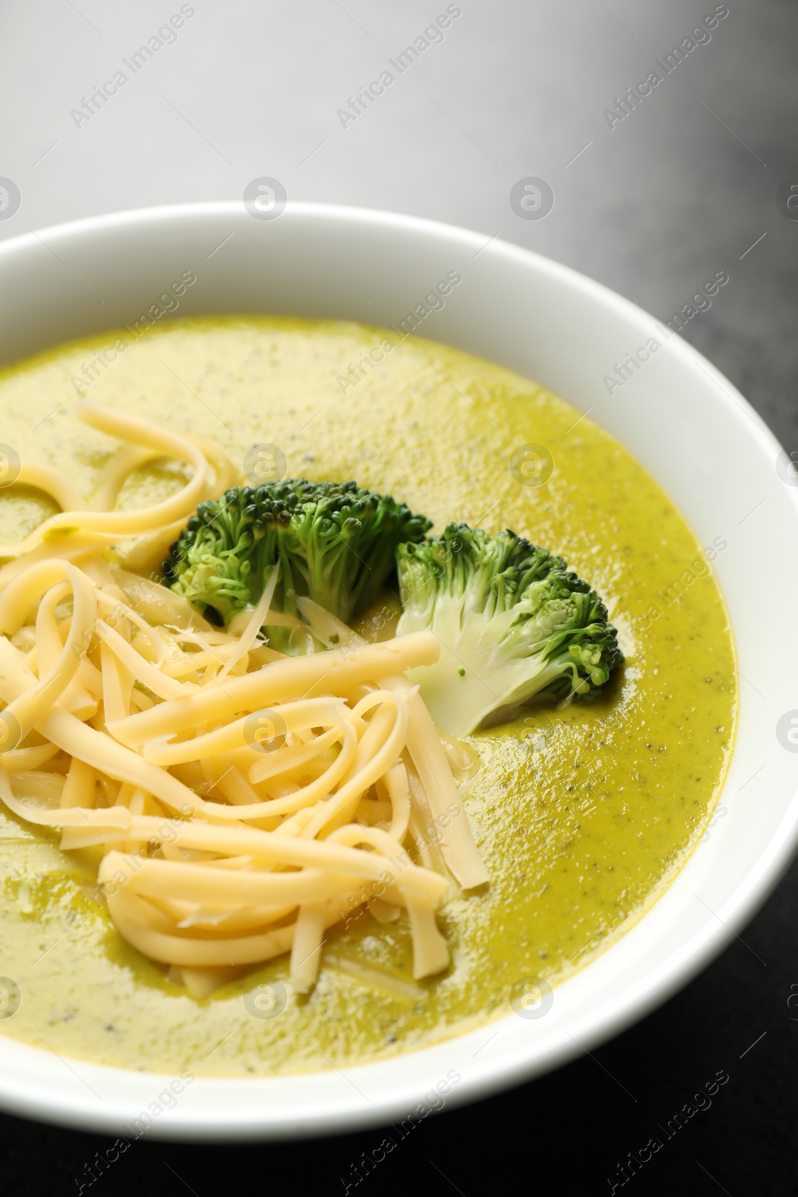 Photo of Delicious broccoli cream soup in bowl on gray table, closeup