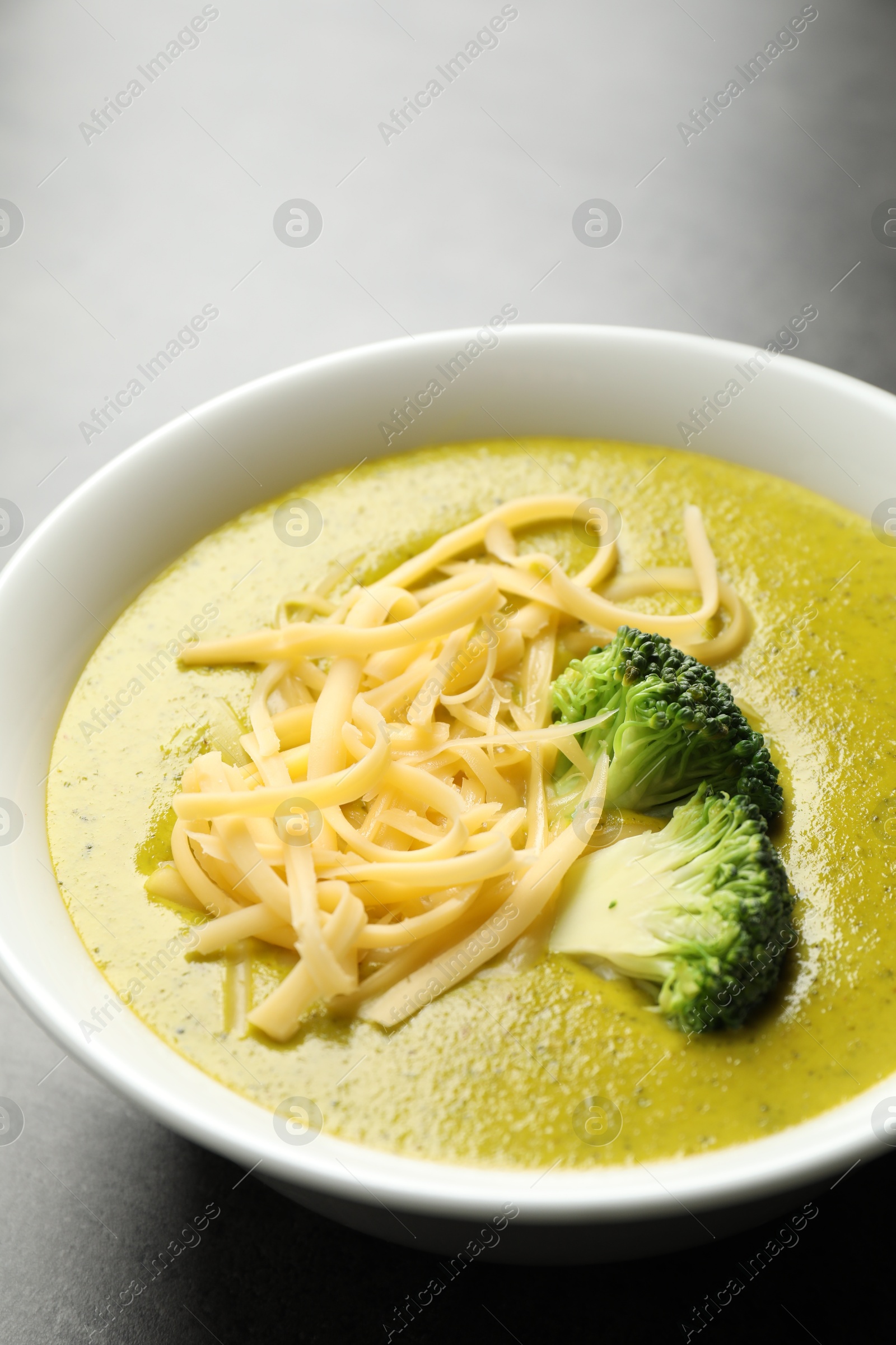 Photo of Delicious broccoli cream soup in bowl on gray table, closeup