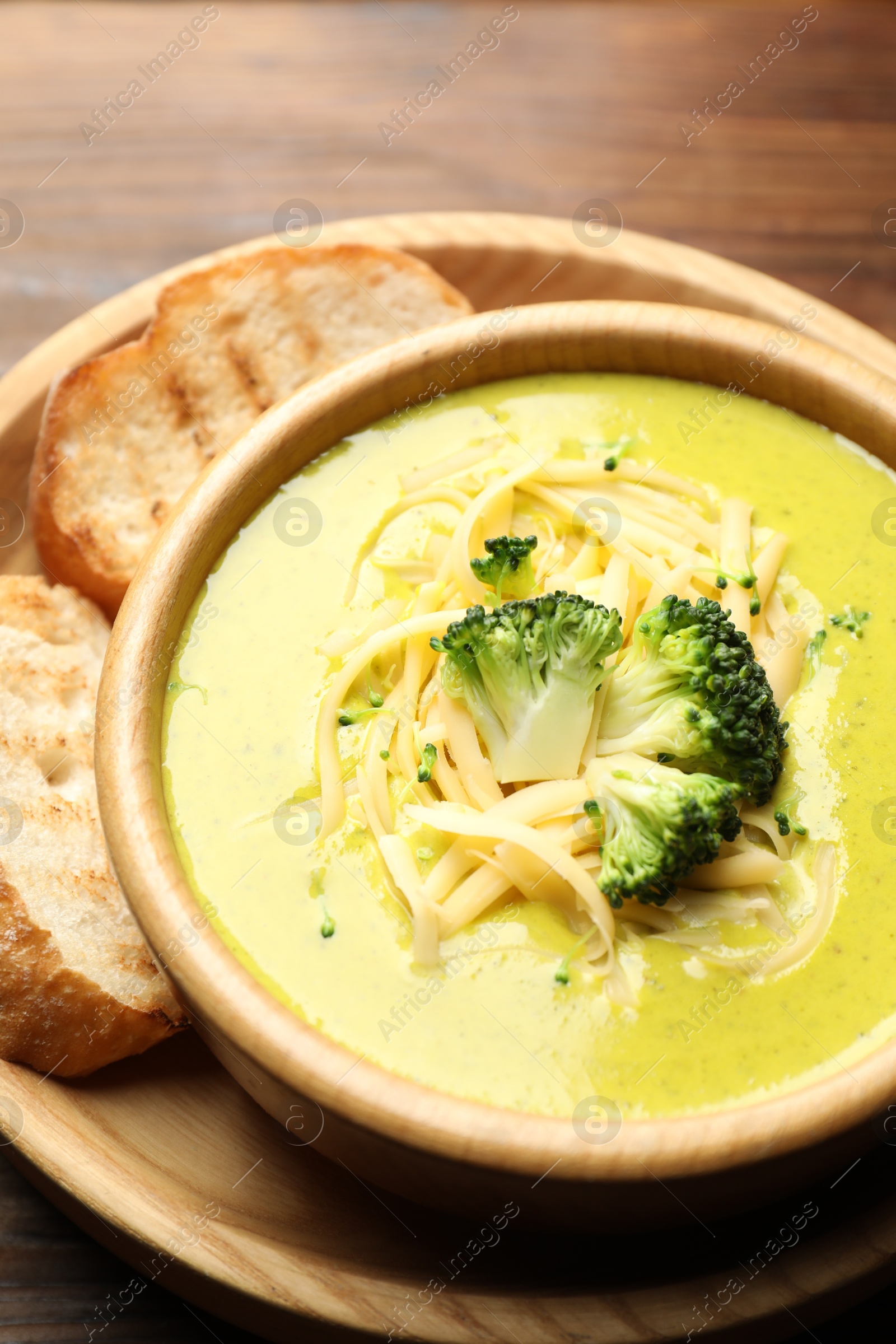 Photo of Delicious broccoli cream soup in bowl and croutons on table, closeup