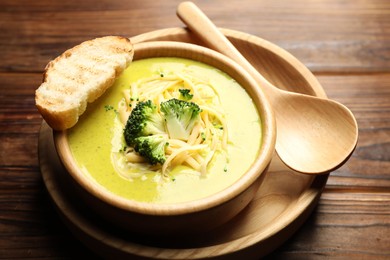 Photo of Delicious broccoli cream soup served on wooden table, closeup