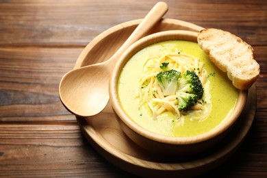 Photo of Delicious broccoli cream soup served on wooden table, closeup