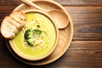 Photo of Delicious broccoli cream soup served on wooden table, top view. Space for text