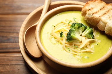 Photo of Delicious broccoli cream soup served on wooden table, closeup