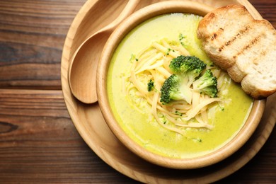 Photo of Delicious broccoli cream soup served on wooden table, top view