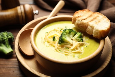 Photo of Delicious broccoli cream soup served on wooden table, closeup