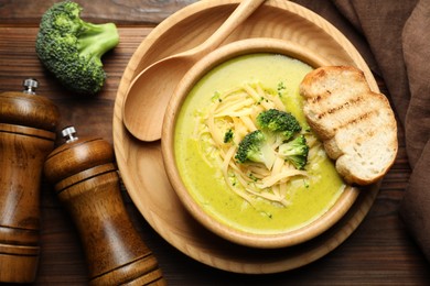 Photo of Delicious broccoli cream soup served on wooden table, flat lay