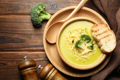 Photo of Delicious broccoli cream soup served on wooden table, flat lay