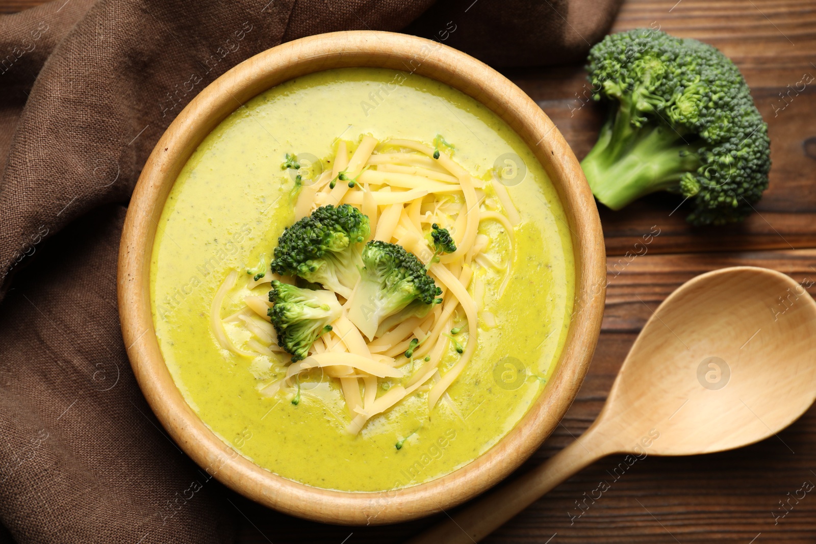 Photo of Delicious broccoli cream soup served on wooden table, flat lay