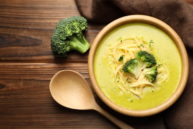 Photo of Delicious broccoli cream soup served on wooden table, flat lay. Space for text