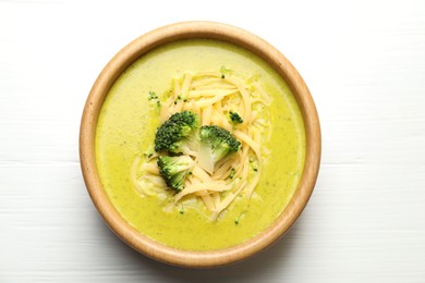 Photo of Delicious broccoli cream soup in bowl on white wooden table, top view