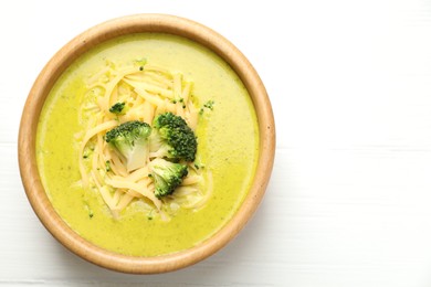 Photo of Delicious broccoli cream soup in bowl on white wooden table, top view. Space for text