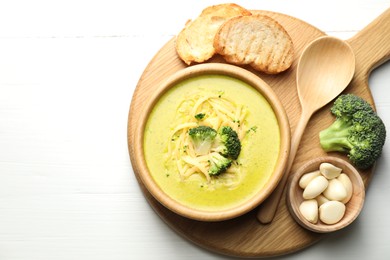 Photo of Delicious broccoli cream soup served on white wooden table, flat lay. Space for text