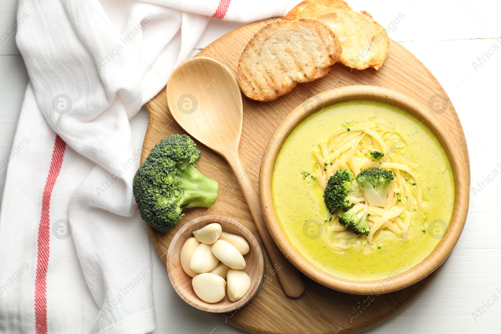 Photo of Delicious broccoli cream soup served on white wooden table, flat lay