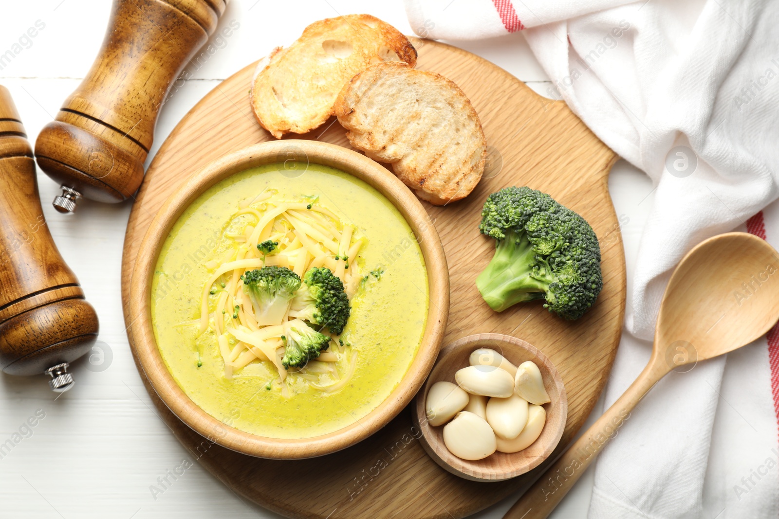 Photo of Delicious broccoli cream soup served on white wooden table, flat lay