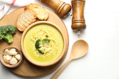 Photo of Delicious broccoli cream soup served on white wooden table, flat lay. Space for text