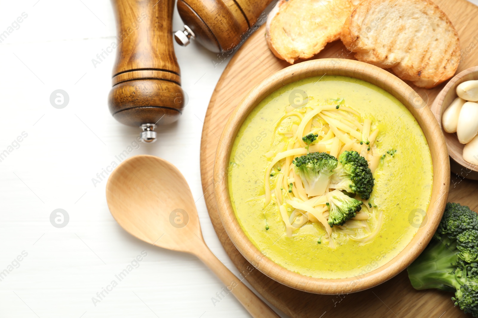 Photo of Delicious broccoli cream soup served on white wooden table, flat lay