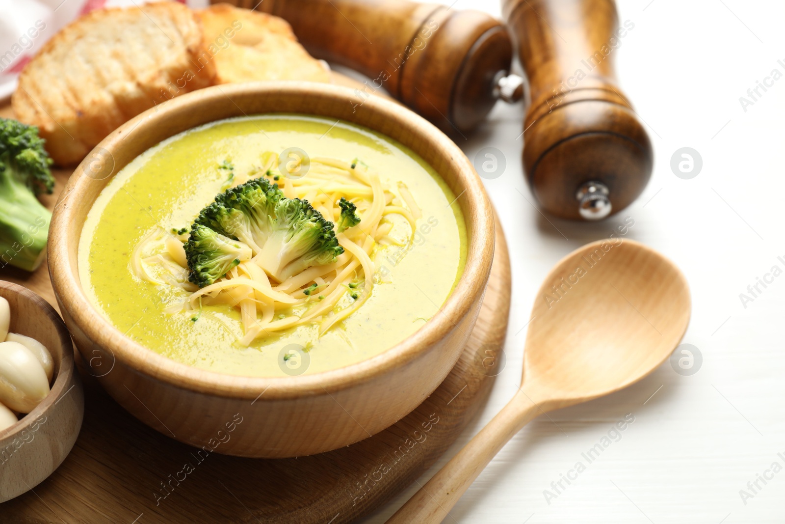 Photo of Delicious broccoli cream soup served on white wooden table, closeup