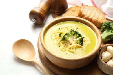 Photo of Delicious broccoli cream soup served on white wooden table, closeup