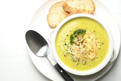 Photo of Delicious broccoli cream soup served on white wooden table, flat lay