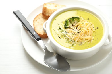 Photo of Delicious broccoli cream soup served on white wooden table, closeup