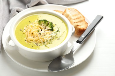 Photo of Delicious broccoli cream soup served on white wooden table, closeup