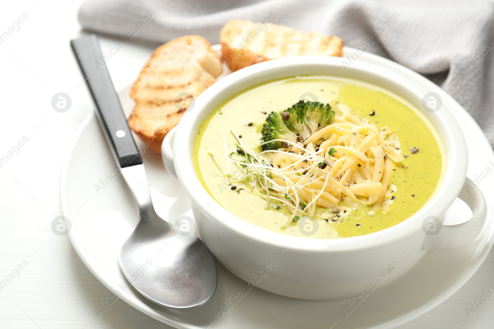 Photo of Delicious broccoli cream soup served on white wooden table, closeup