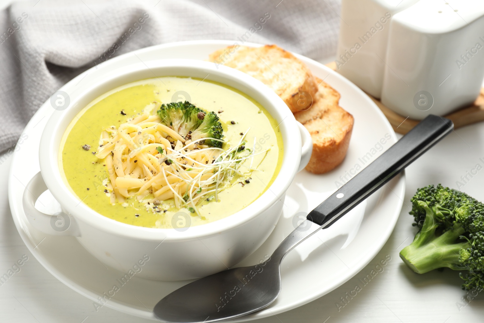 Photo of Delicious broccoli cream soup served on white wooden table, closeup